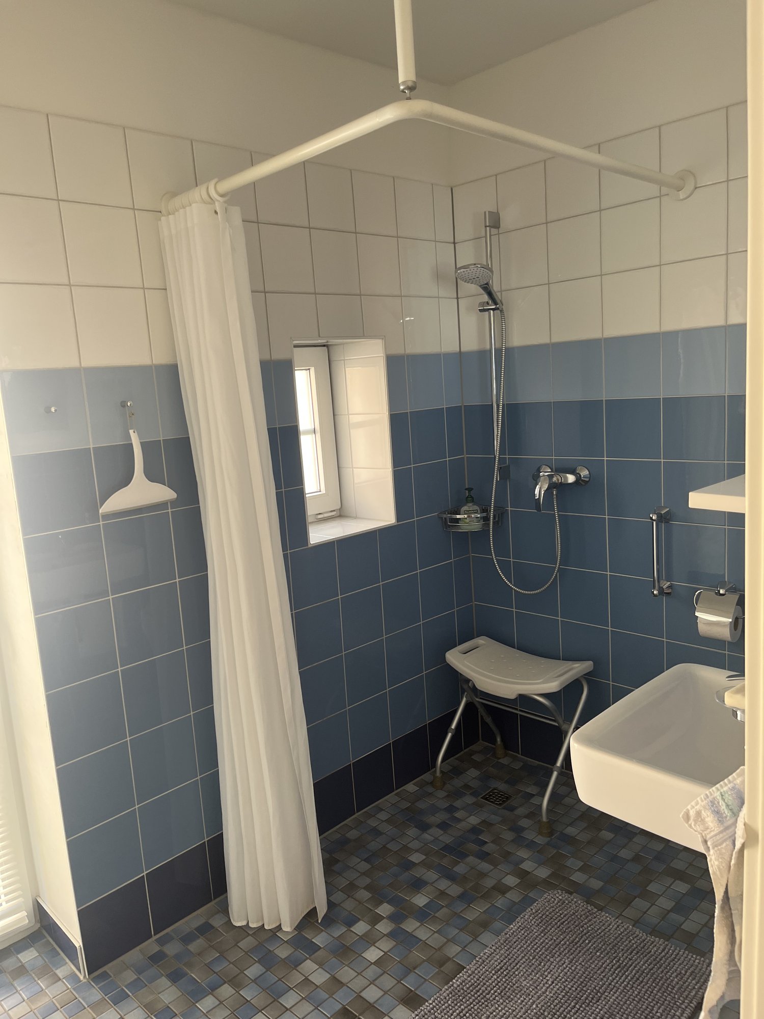 Badezimmer mit ebener Dusche, Duschhocker und Haltegriff