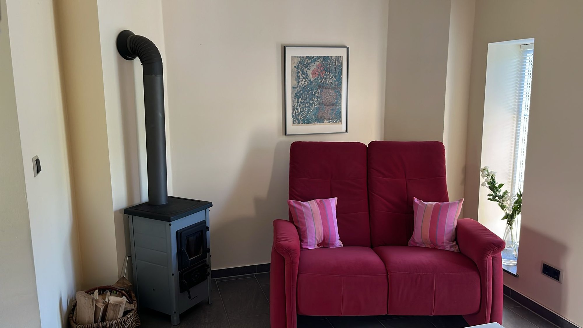 Wohnzimmer mit rotem Sofa und Kaminofen